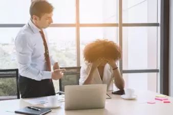 Businessman speaking with frustrated female employee at desk