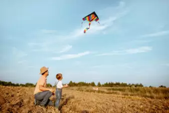 Father and son flying kite in open field