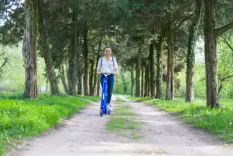 Woman using an electric scooter in a tree-lined area