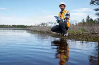 Marine biologist kneeling by the water