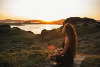 Woman meditating outside by the sunset