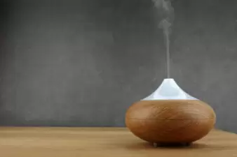 Aroma oil diffuser on wooden table and grey background