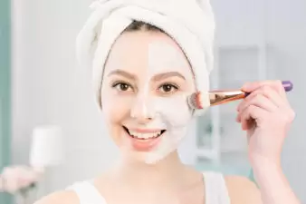 Woman putting on face cream using a makeup brush