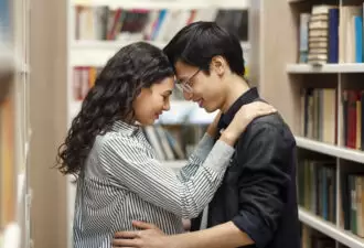 Two students hugging in library