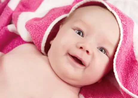 Adorable baby girl in pink blanket smiling