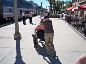 person pushing another person in a wheelchair at a train station