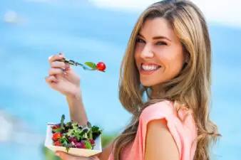 woman smiling as she eats a salad