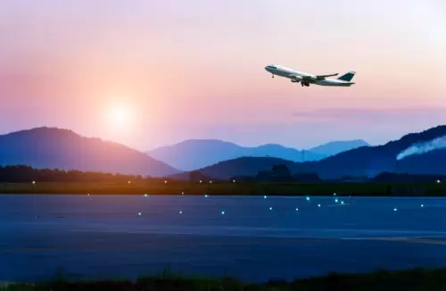 passenger plane fly up over take-off runway from airport at sunset