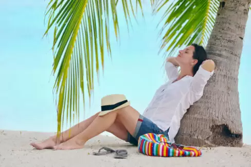 Woman laying back against a tree in tropical location