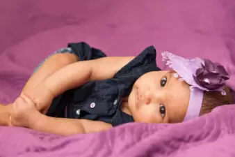 Black baby girl wearing purple bow on purple blanket