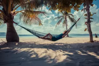 Woman relaxing in hammock on tropical beach