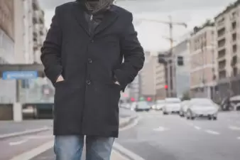 Closeup of man wearing a black coat with hands in pockets