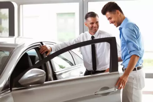 Car salesman showing man a car to buy