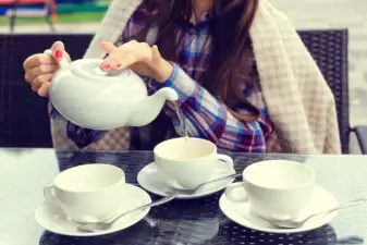 Woman hands pouring tea from a kettle