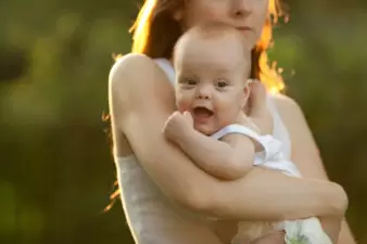 Mother holding her cheerful baby outdoors