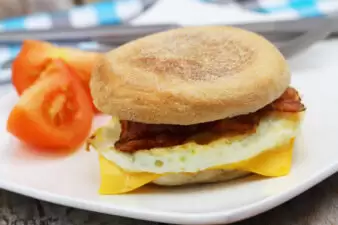 Egg and bacon muffin with tomato slices on the side