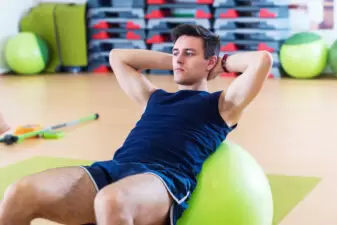 Fit man doing sit-ups on exercise ball