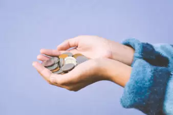 Hands holding coins on a light purple background