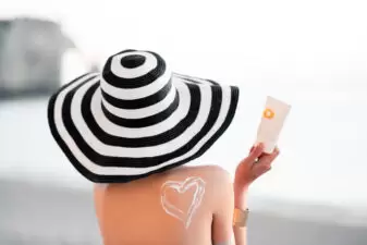 woman putting on heart in sunscreen on back