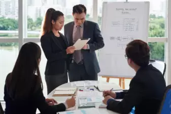 Woman and man discussing a project with a business team