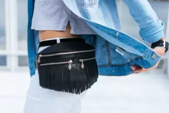 woman with a fringe black waist bag and denim jacket