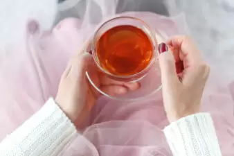 woman on the bed with old book and cup of tea