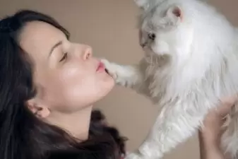 Woman making kissy face at her white cat