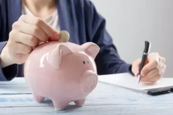 hand putting money into a piggy bank