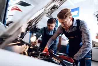 Two men working on car engine