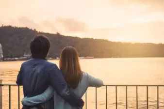 young couple watching the sunset over water