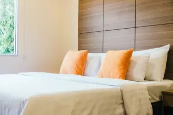 comfortable bed with tan comforter and tan and orange pillows