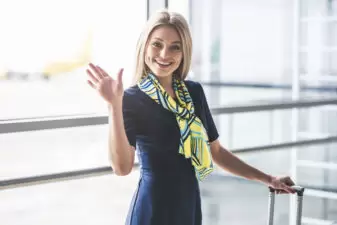 Friendly flight attendant waving in airport