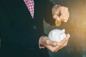 businessman putting coin into a piggy bank