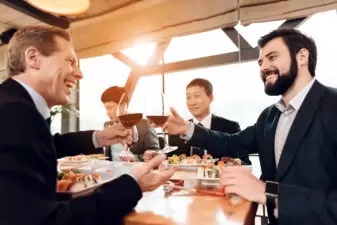 Men at a business dinner doing cheers with wine glasses