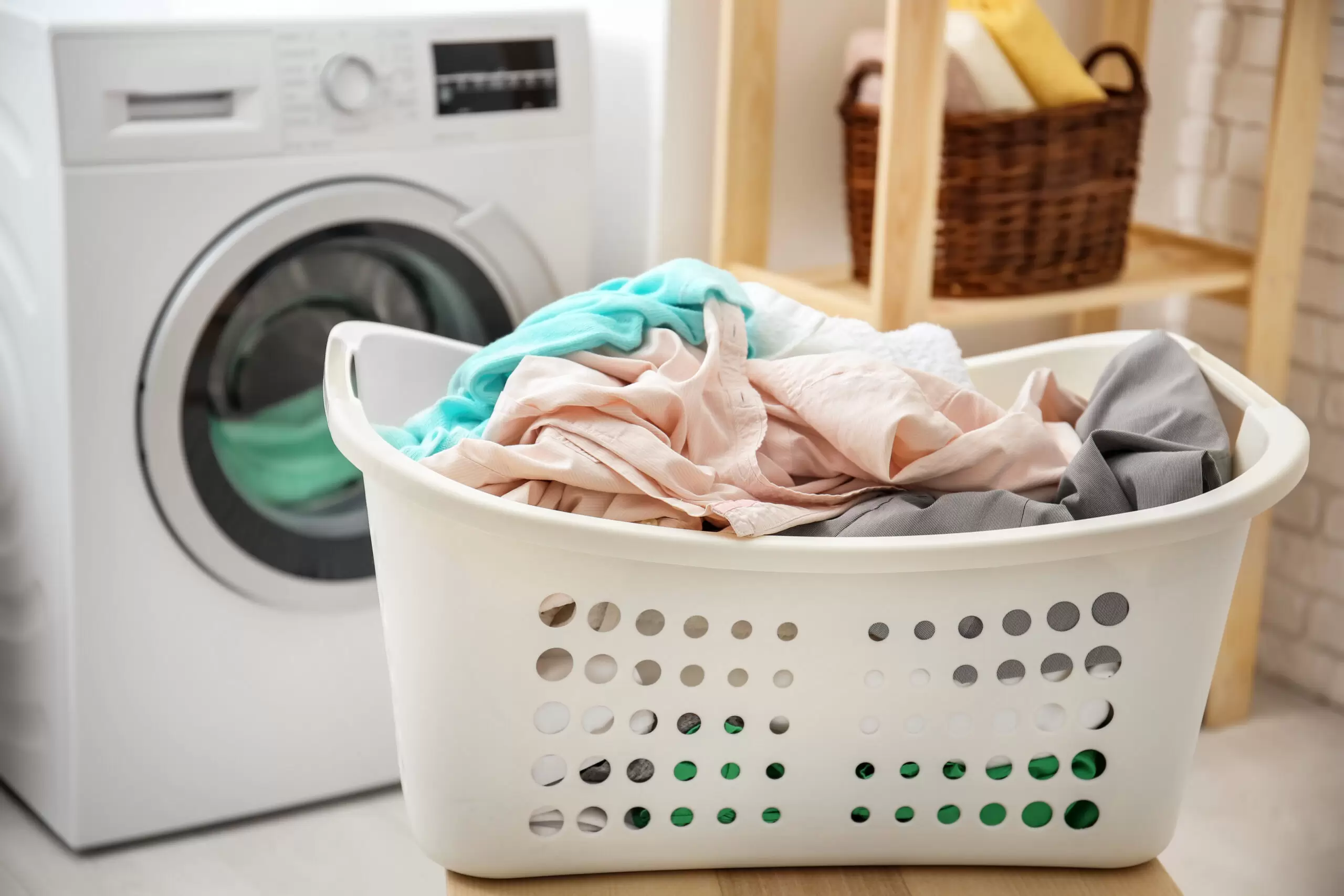 Basket with laundry and washing machine in bathroom