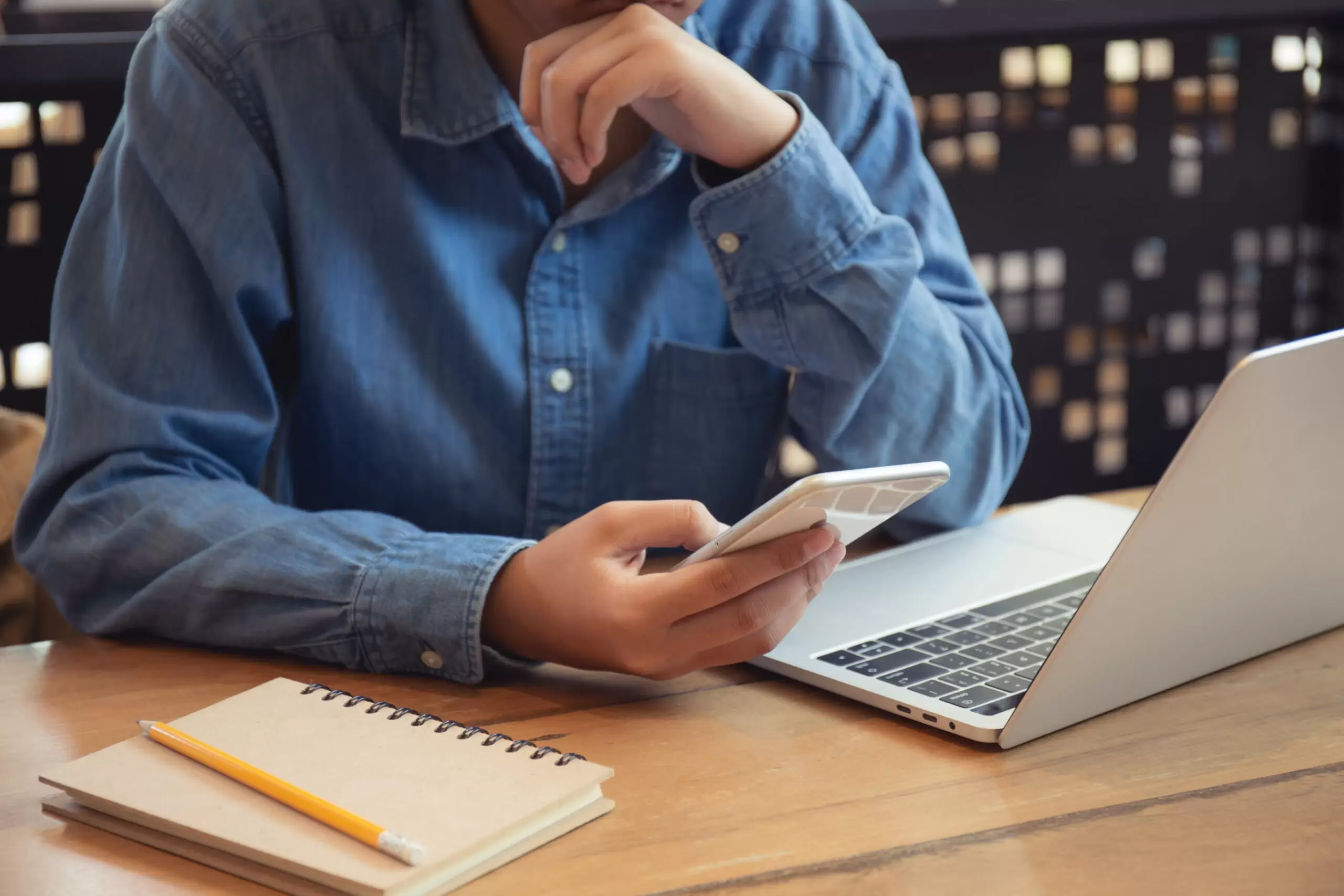 person working at desk with phone and laptop