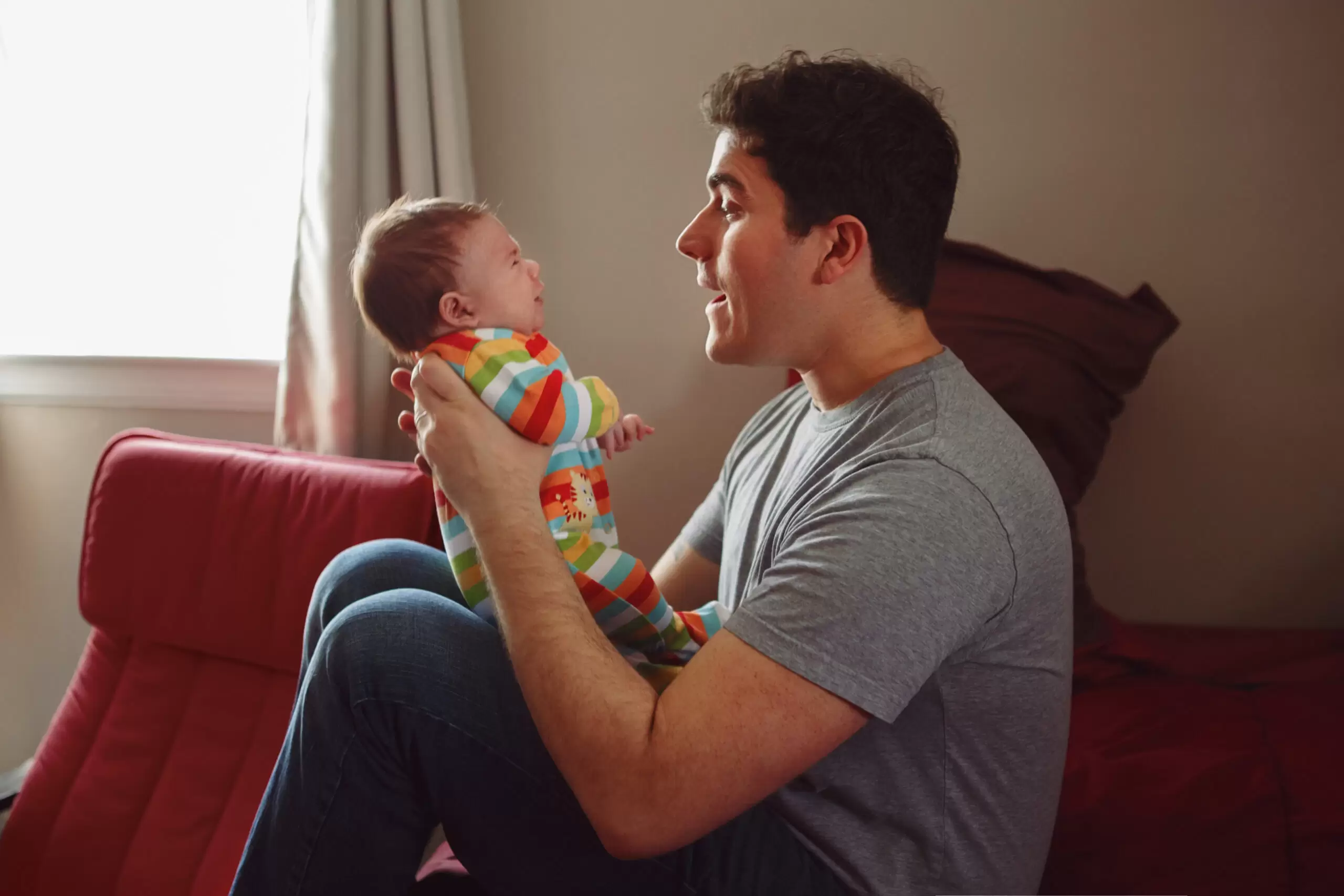 man trying to get crying baby to laugh