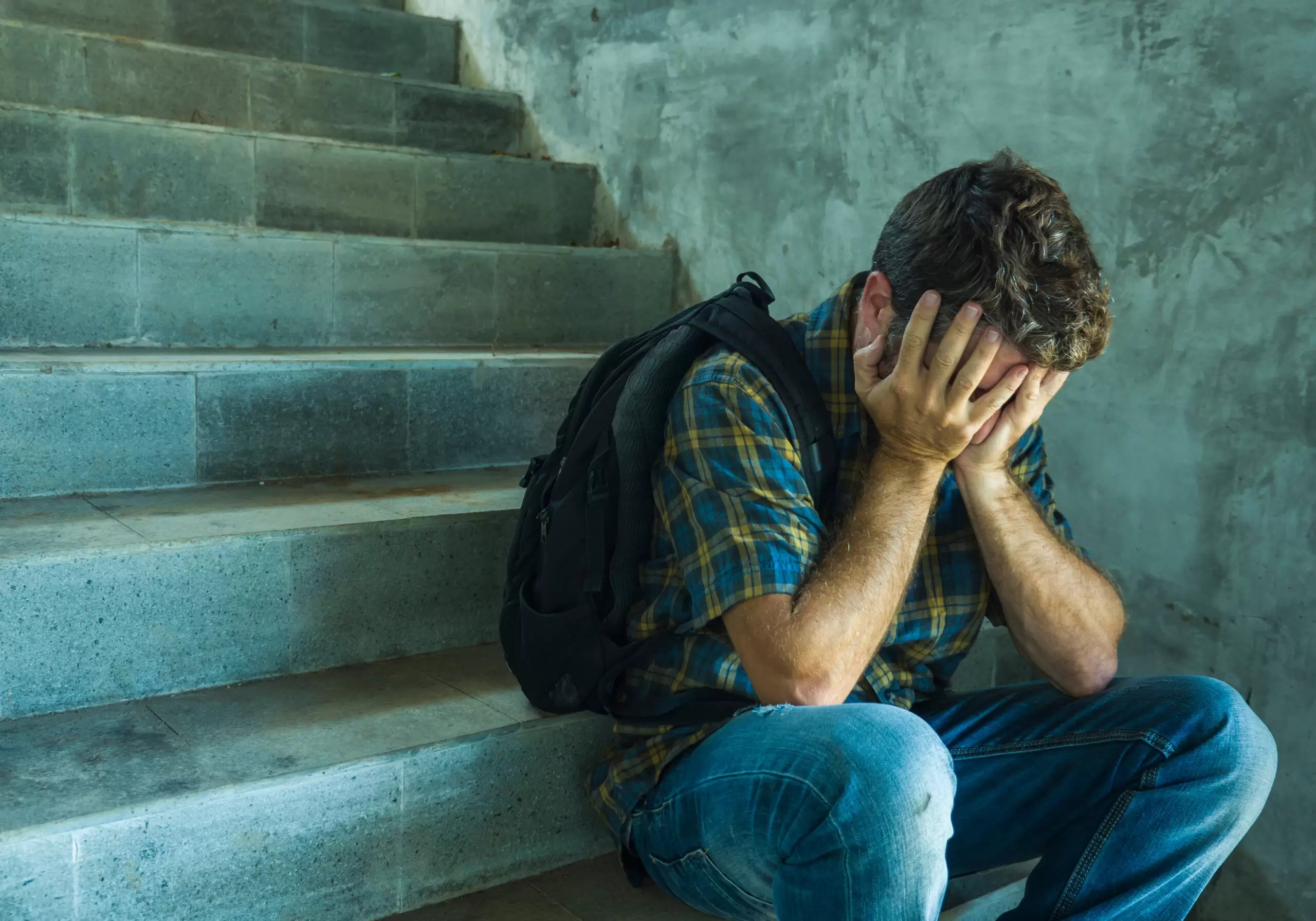 Campaign vs homophobia with young sad and depressed college student man sitting on staircase desperate victim of harassment suffering bullying and abuse