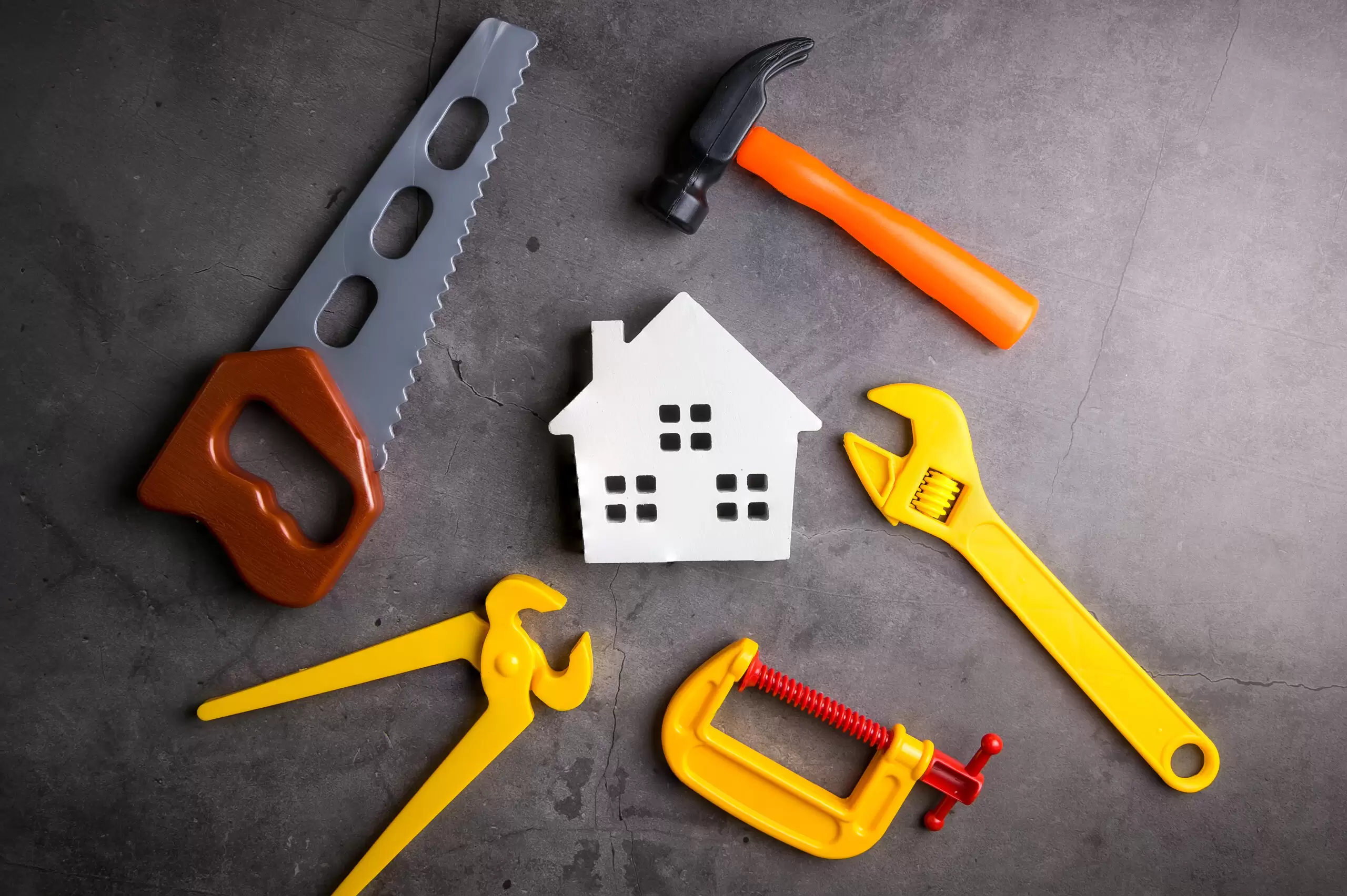 Wooden house and construction tools toy on stone pattern background