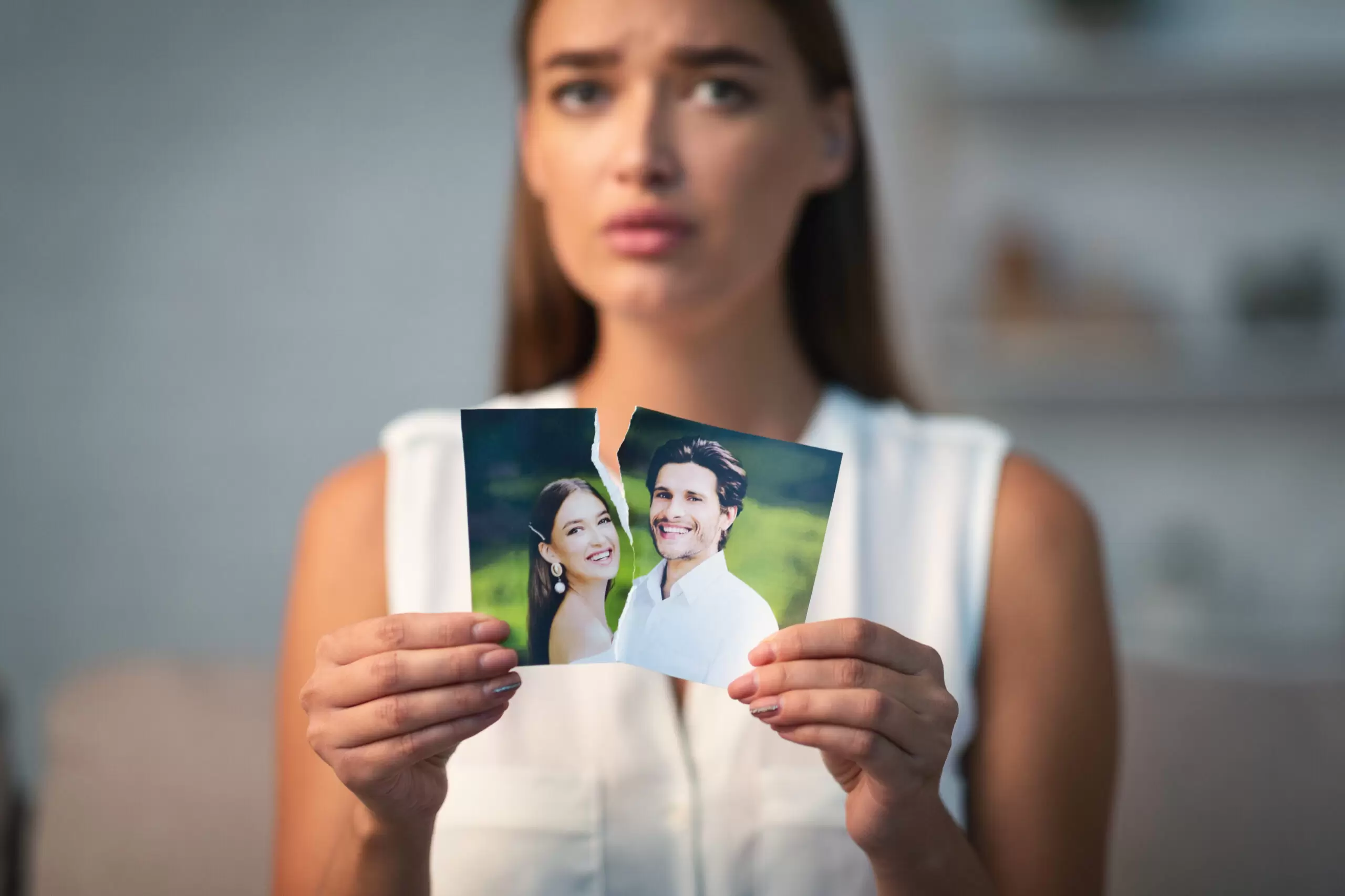 Sad girl ripping up couple photo