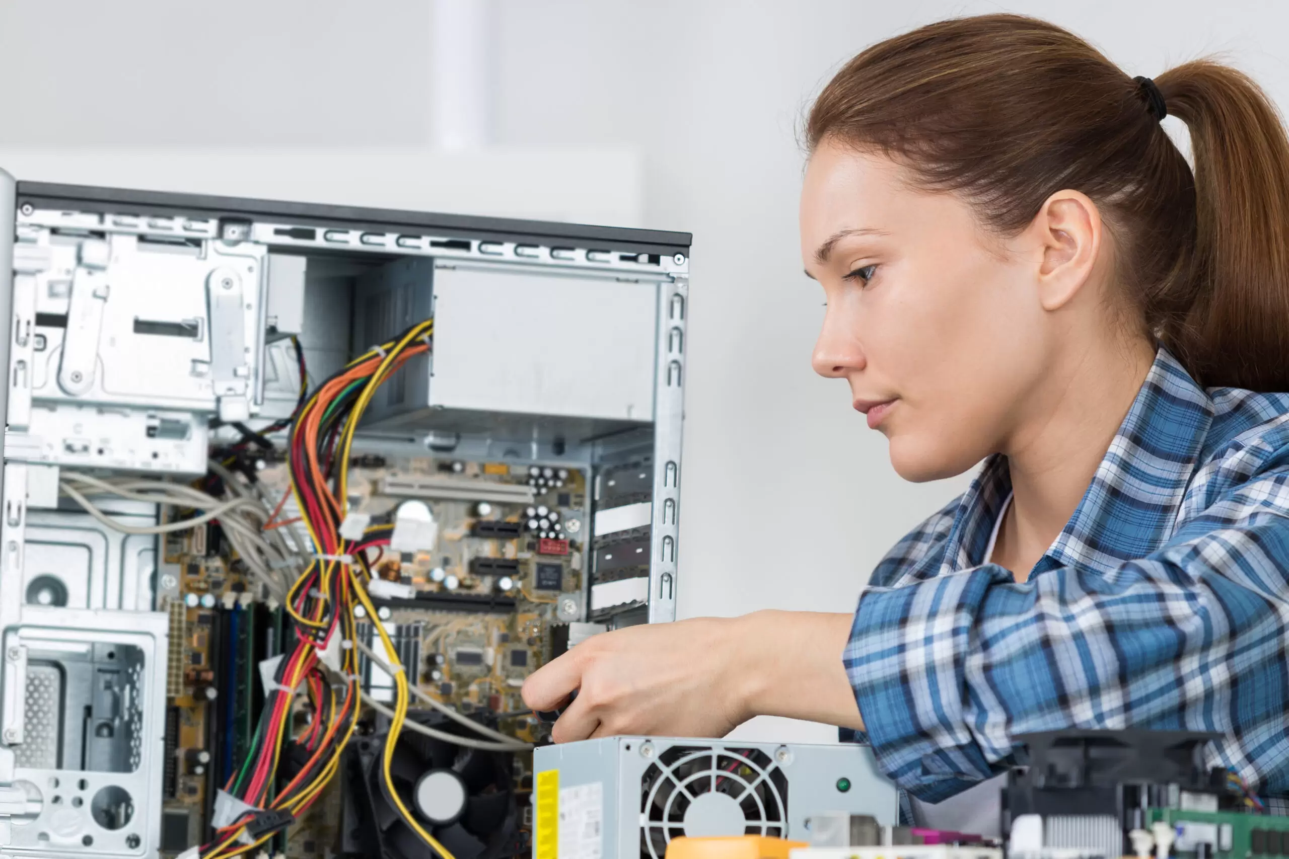 young woman fixing computer at desk at work