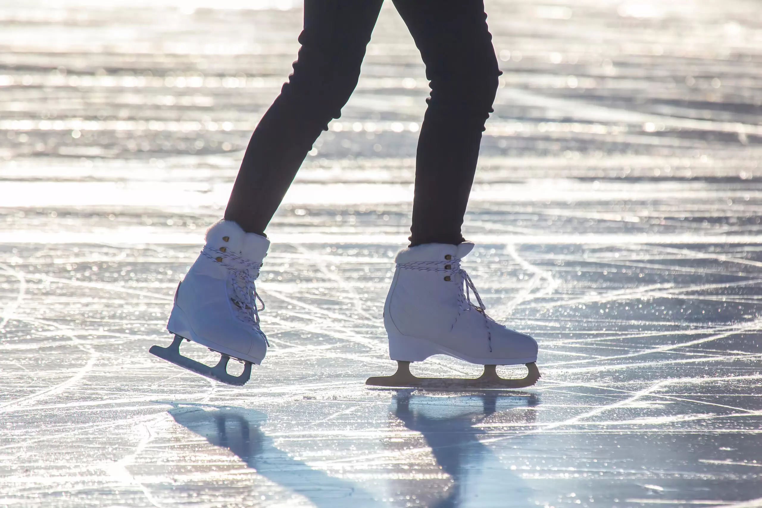 Female legs in white skates on an ice rink