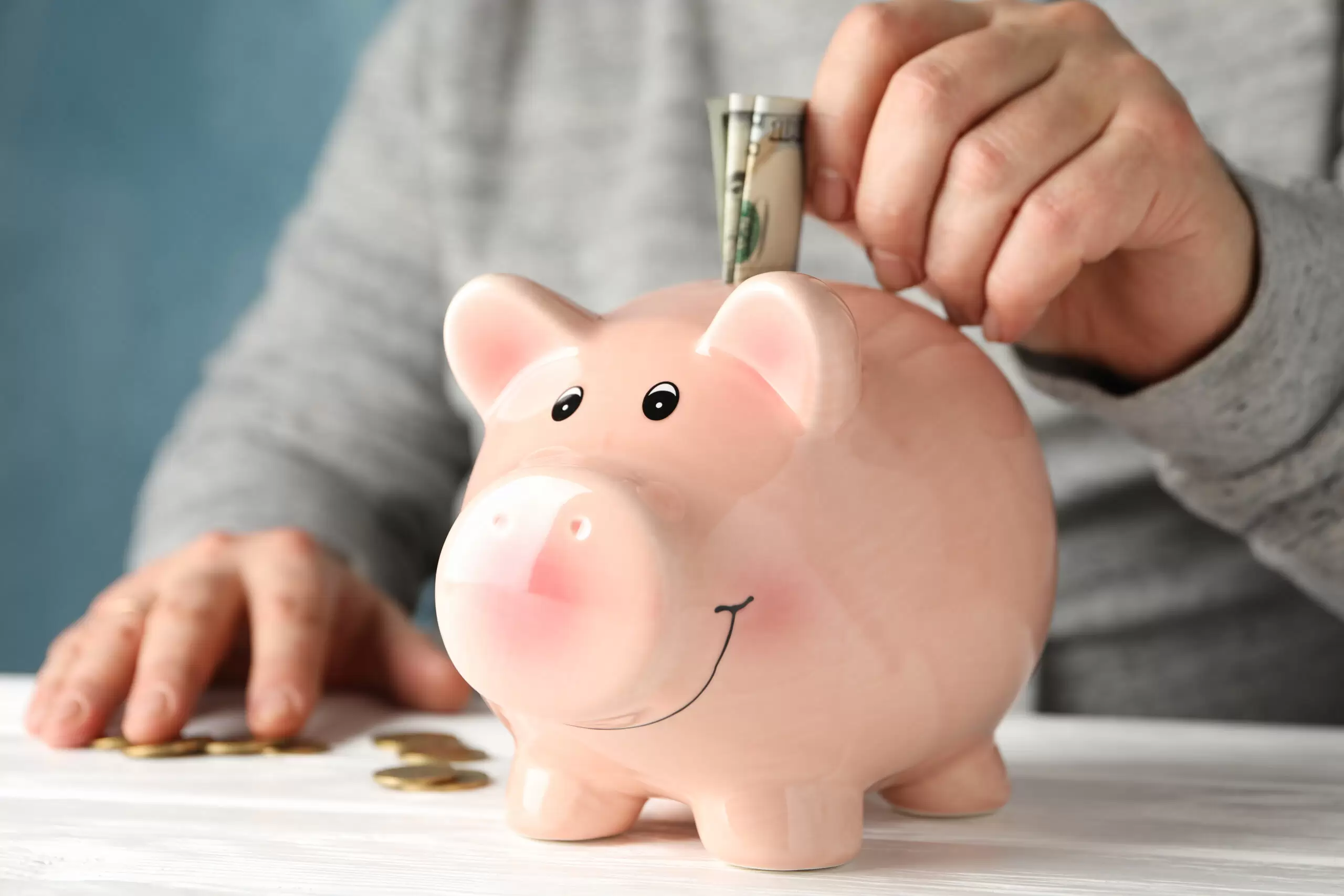 Man's hand putting cash in piggy bank