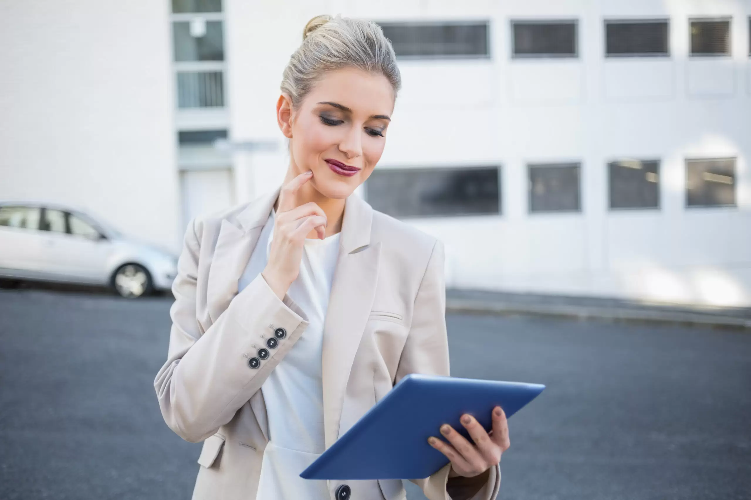 Pensive stylish businesswoman using digital tablet outside on urban background