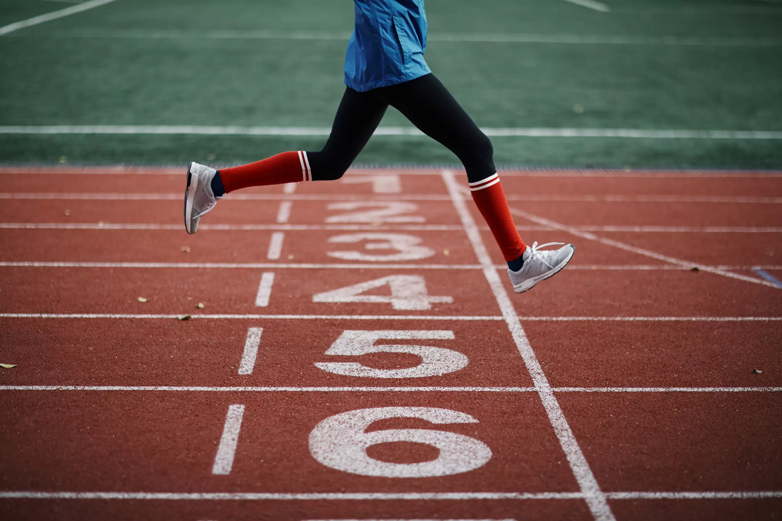 Male runner legs crossing the finish line on track