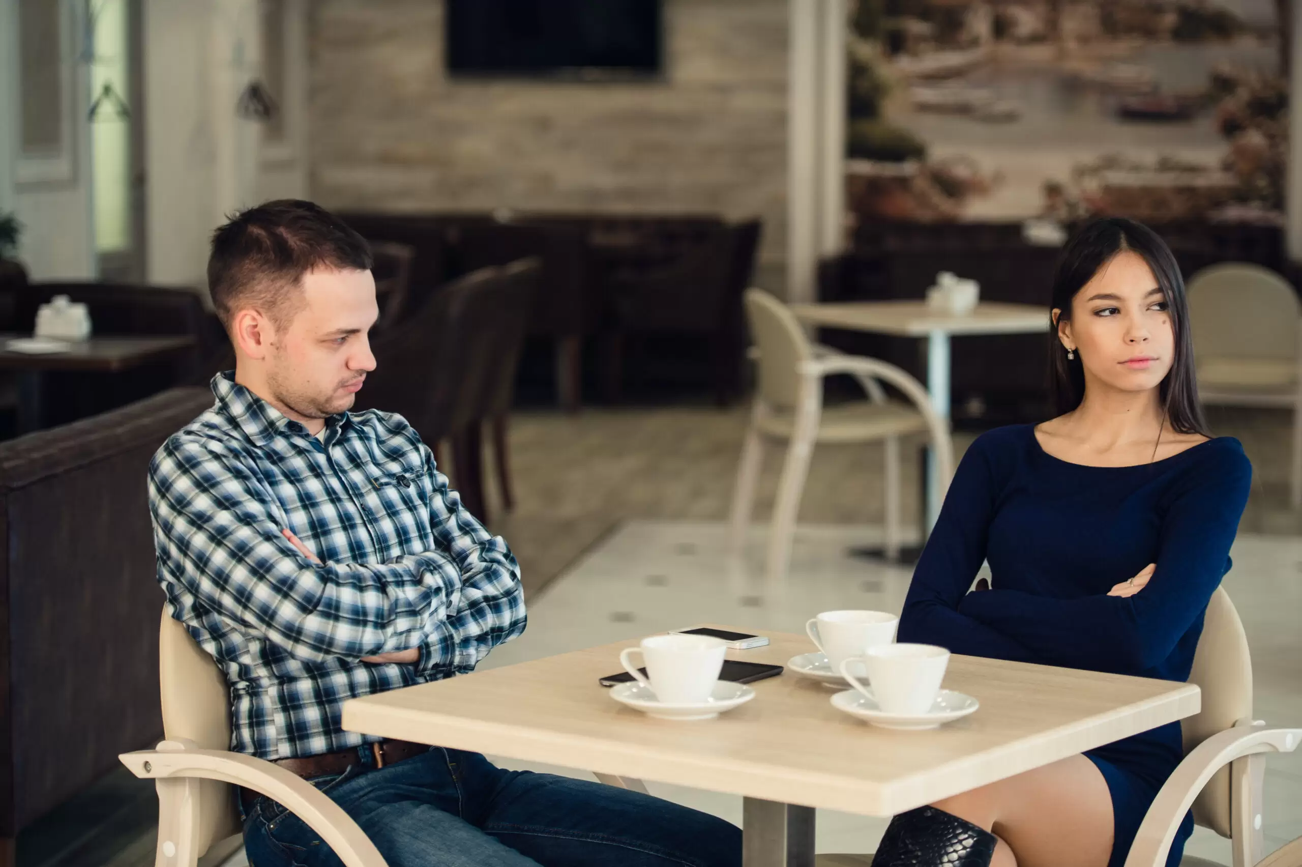 Young unhappy married couple having serious quarrel at cafe