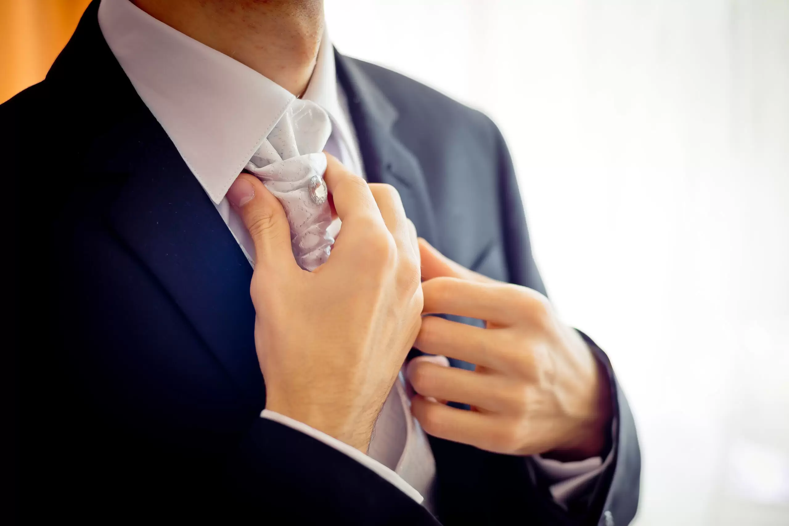 Close-up view of the groom hands correcting the cravat before the wedding ceremony.